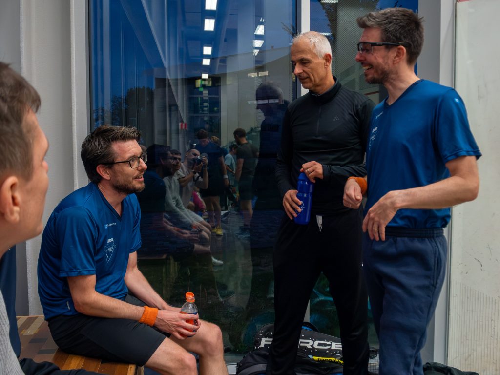 Three club members talking beside the squash courts.
