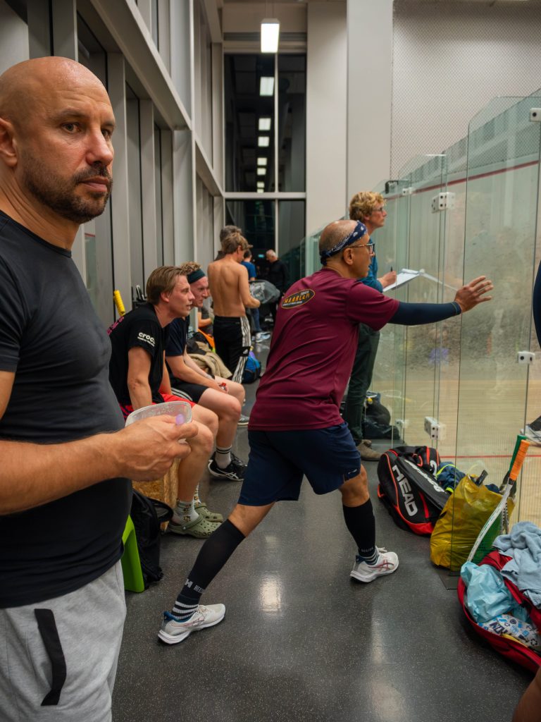 Players and spectators gathered beside the glass squash court during league opening night.