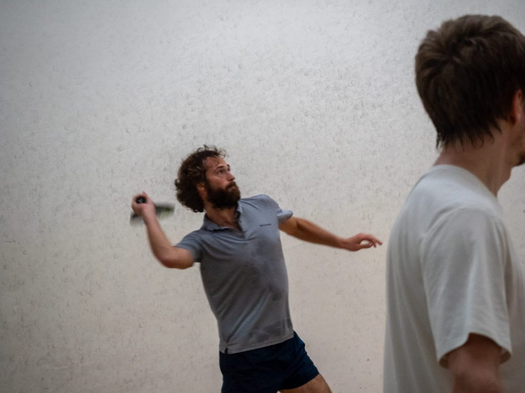 A player in a grey shirt prepares a racket swing during a rally.