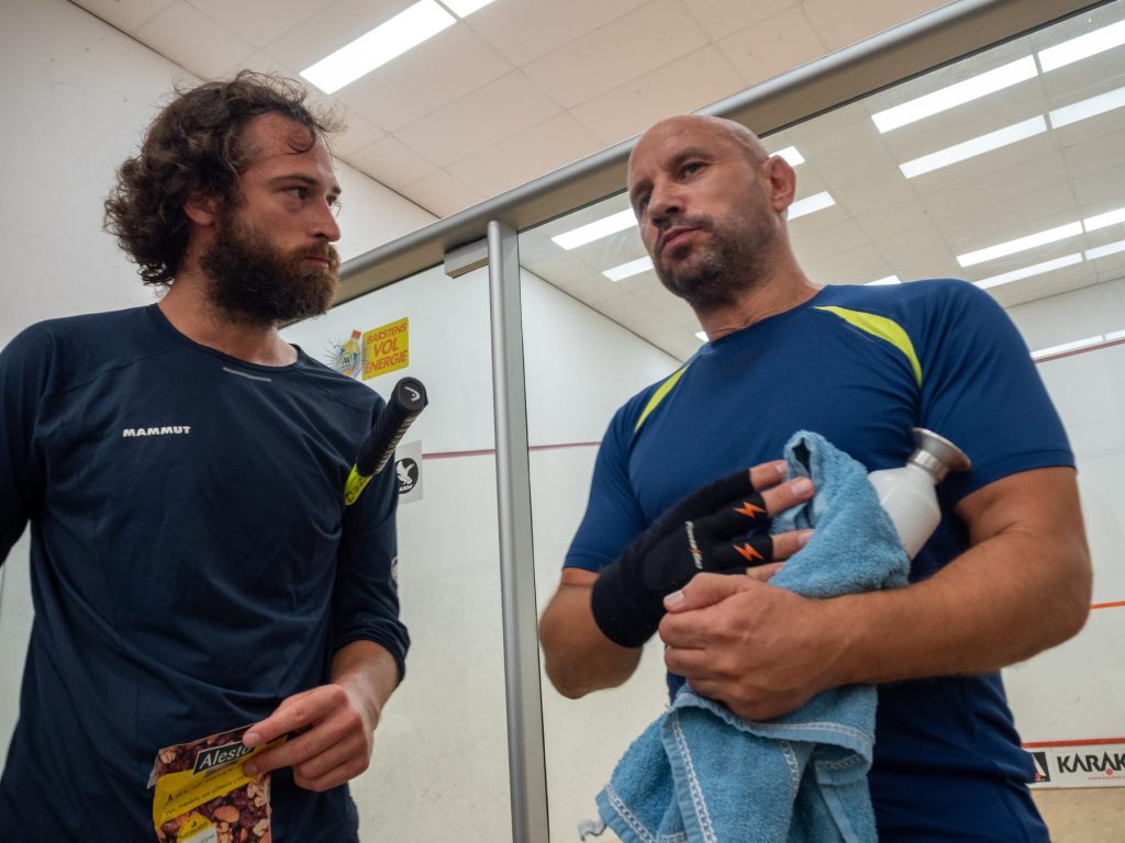 Two players talking beside the glass court after a match.