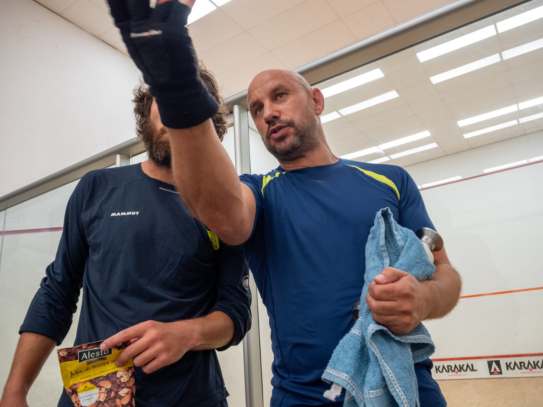 Two players discussing a rally beside the squash court.