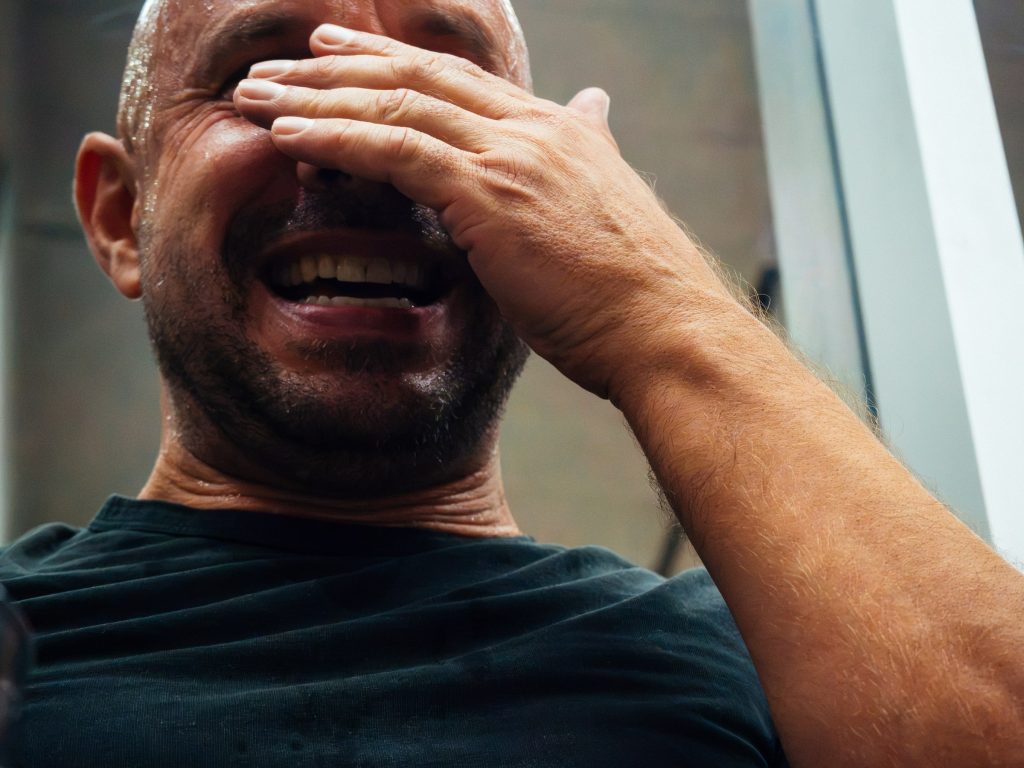 A player laughs with his hand over his face beside the court.