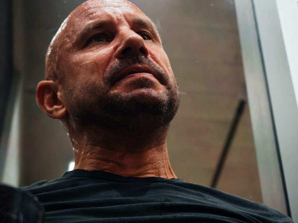 A player in a dark shirt watching from beside the court.