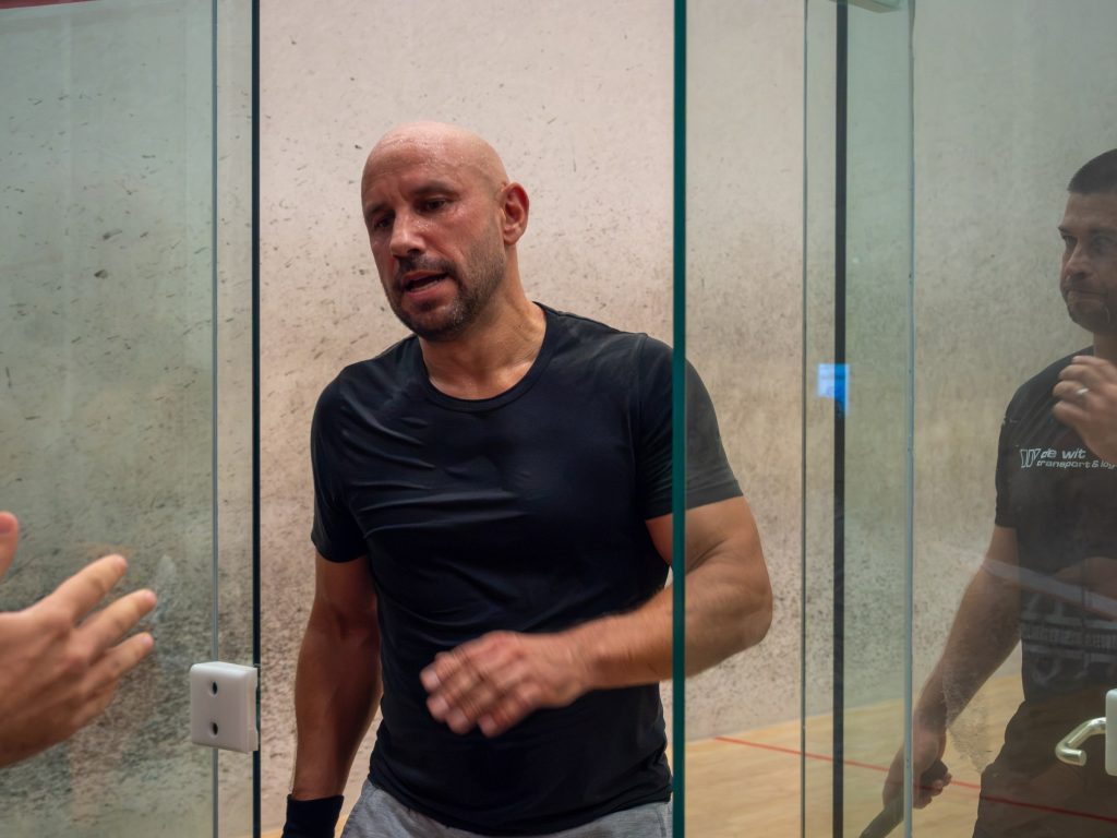 A player talking at the glass door of the squash court.