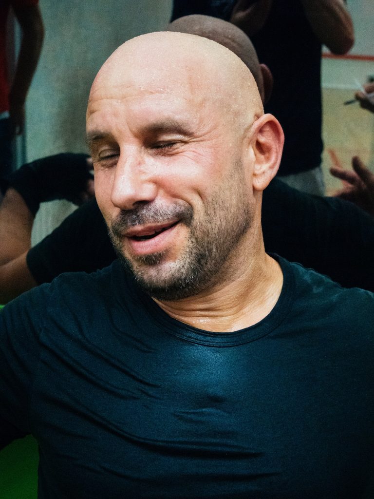 A player smiling with his eyes closed beside the court.