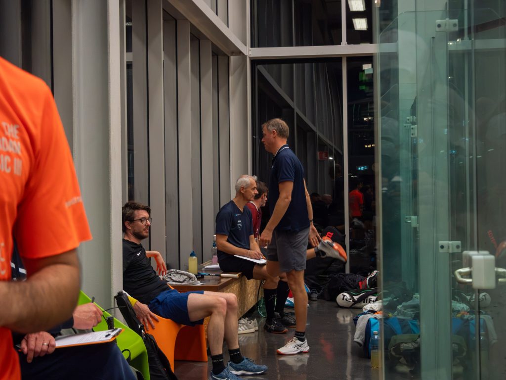 Players gathering beside the glass courts during league night.