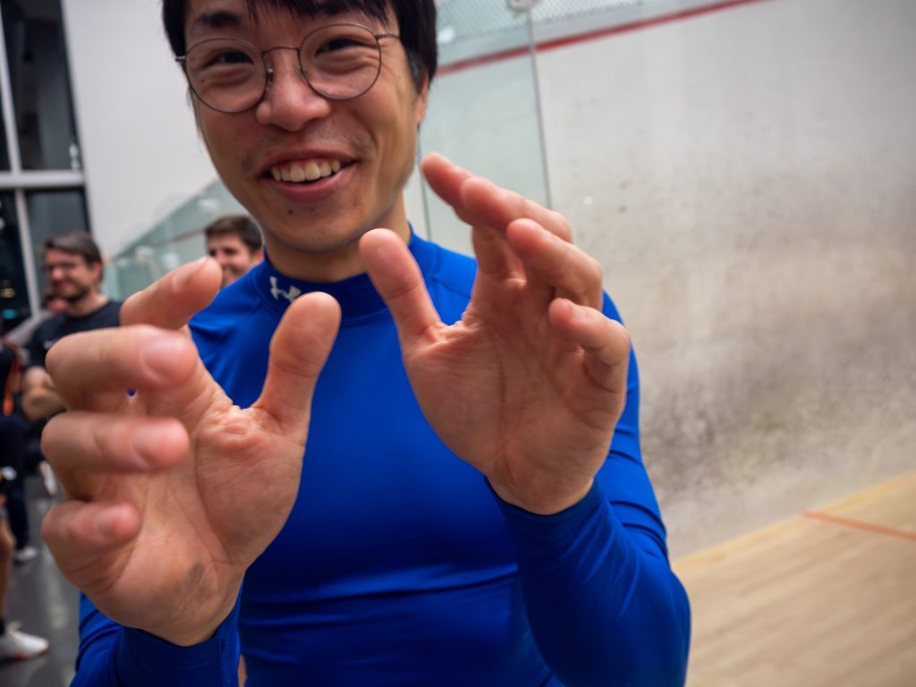 A smiling player in blue gesturing towards the camera.