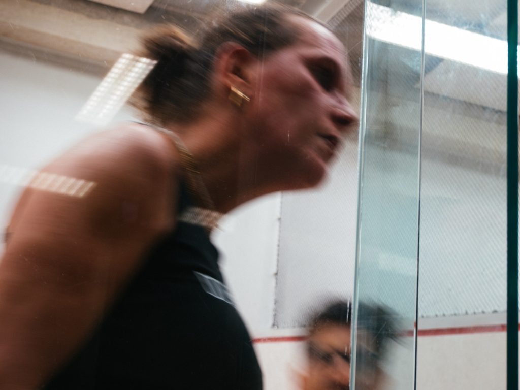 A player in black moving past the glass court door.