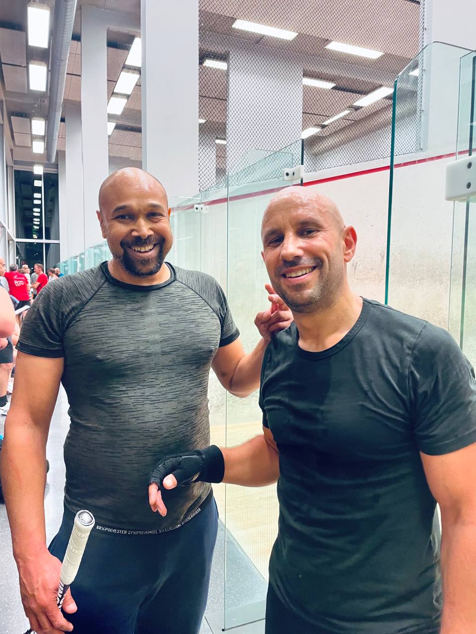 Two players beside the glass squash courts.